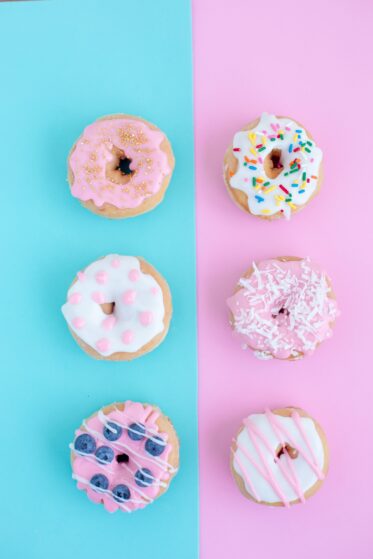 donuts with different toppings on a baby blue and pink background